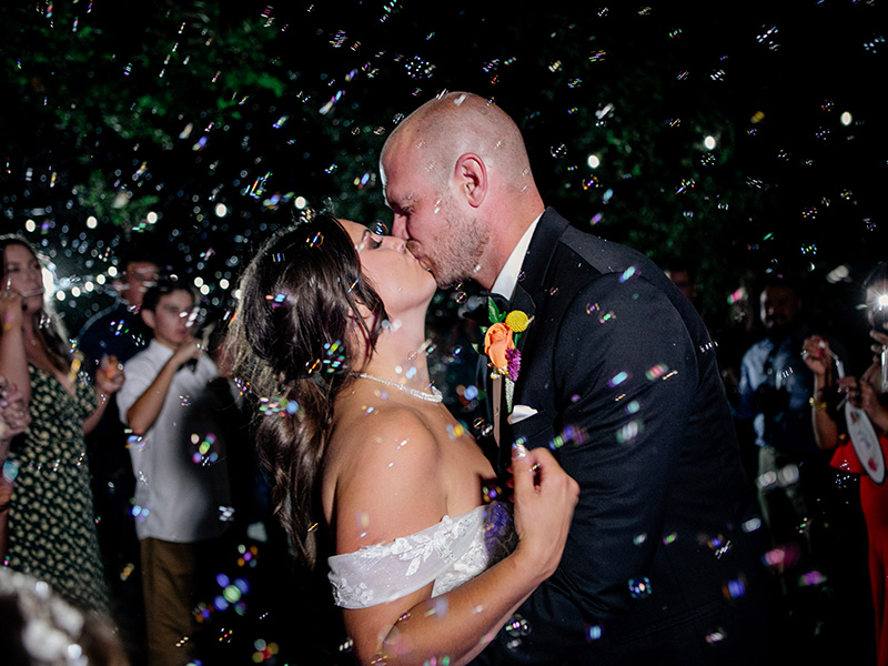 Groom kissing bride at reception at night on the dancefloor